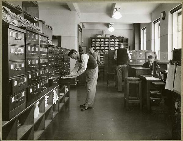 Photo of man researching police records at large filing cabinet